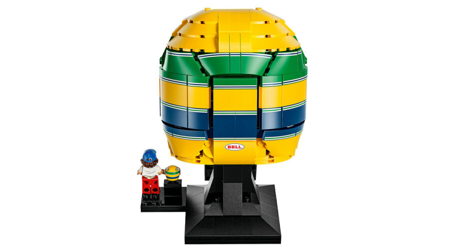 Model Lego przedstawiający żółty, zielony i niebieski kask wyścigowy z minifigurką na czarnym stojaku.