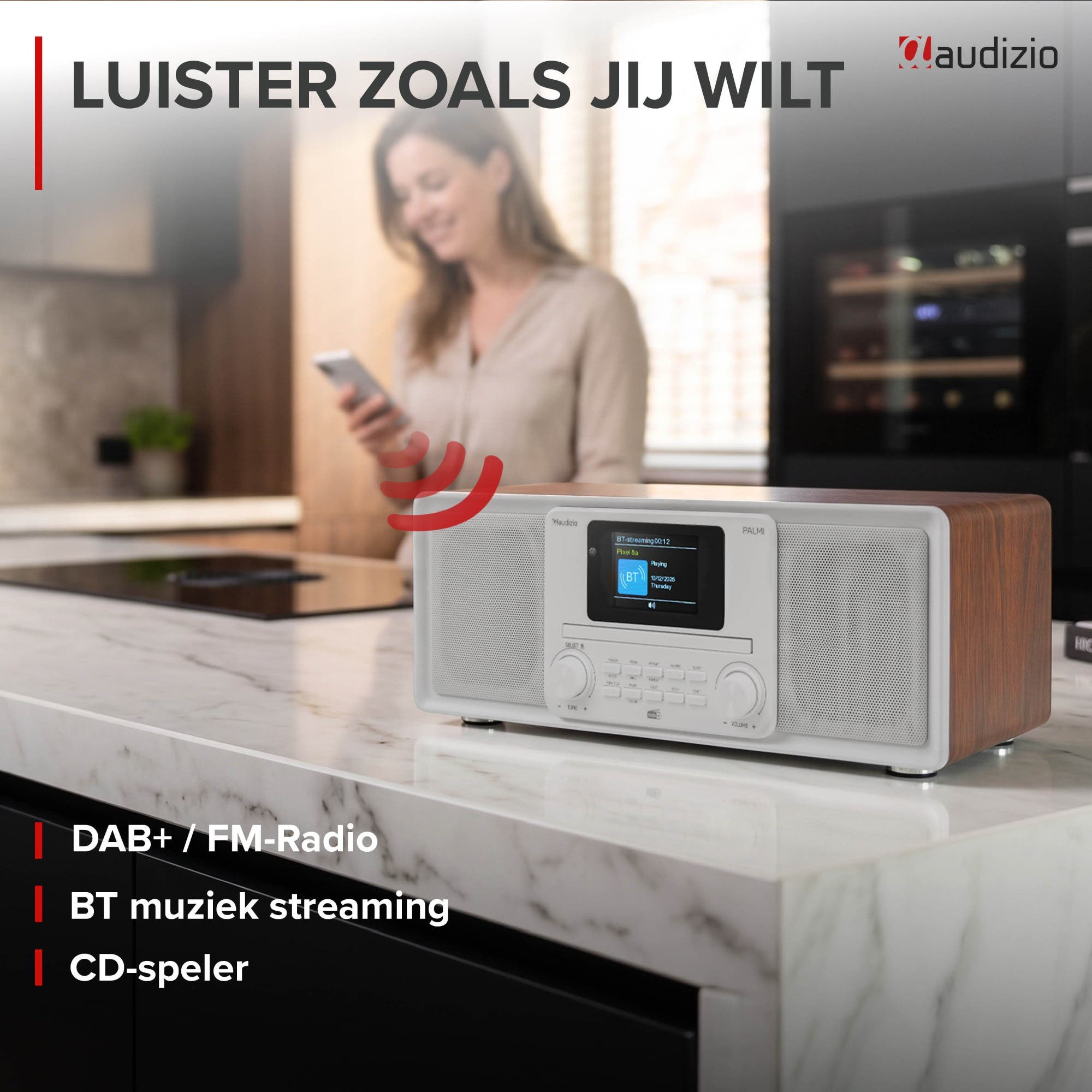 Ein Audizio-Radio mit Holzverkleidung steht auf einer Küchenarbeitsplatte, während im Hintergrund eine Frau ihr Smartphone bedient.