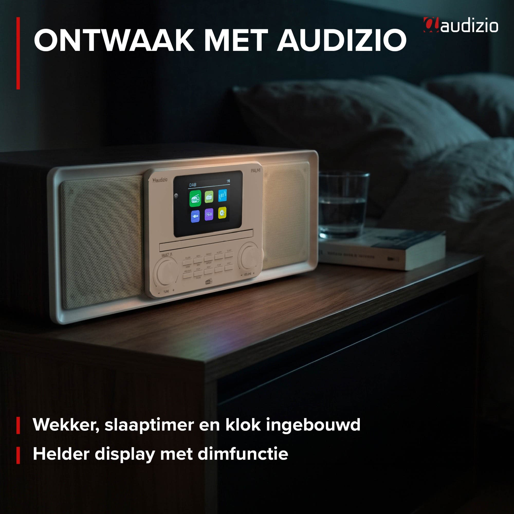 Ein Audizio Radiowecker steht auf einem Nachttisch in einem schwach beleuchteten Schlafzimmer mit Buch und Glas.