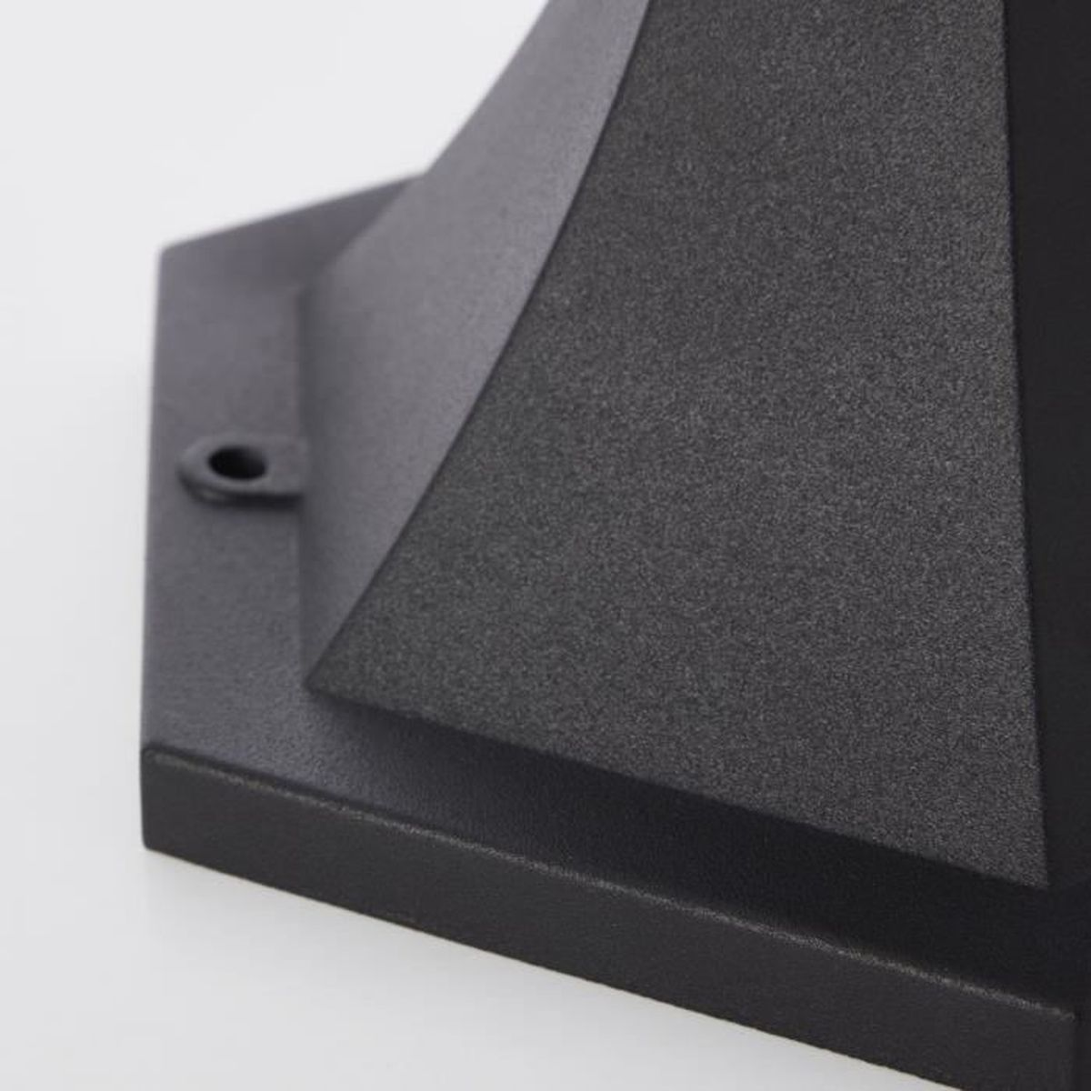 Nahaufnahme einer schwarzen, strukturierten Metallbasis mit einer Öse vor hellem Hintergrund.