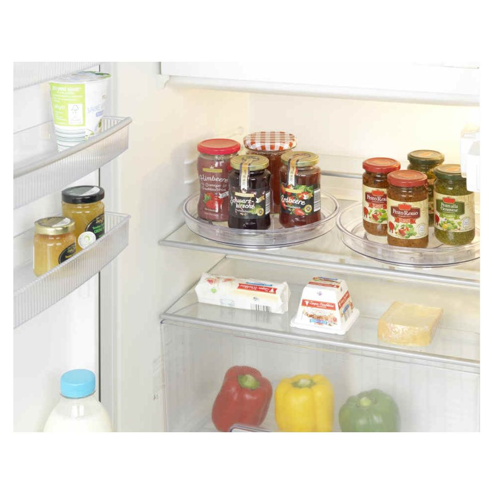 Geordneter Kühlschrank mit Gläsern, Käse, Joghurt und frischem Gemüse in den Fächern.