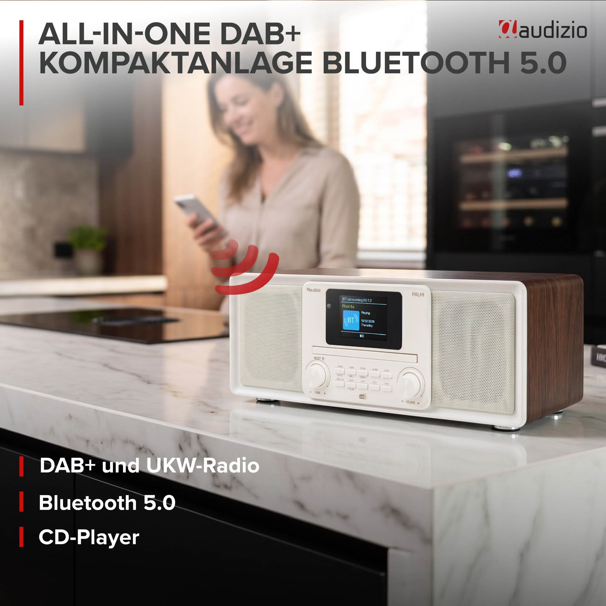 Audizio DAB+ Kompaktanlage in Holzoptik auf einer Marmorarbeitsplatte, verschwommene Frau im Hintergrund.