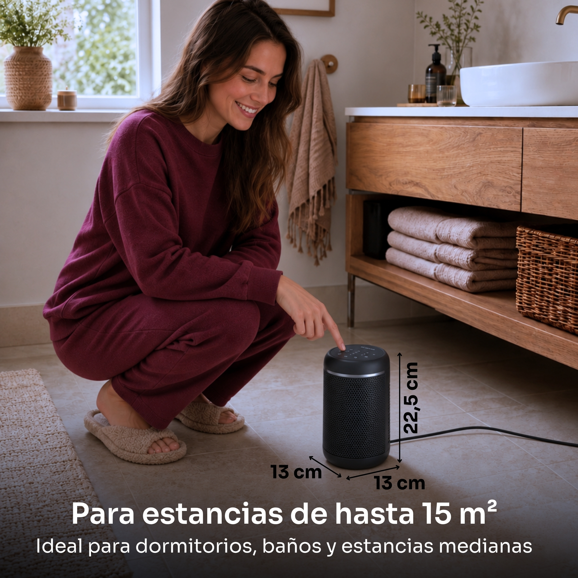 Una mujer con ropa granate toca un deshumidificador cilíndrico negro en el suelo del baño.