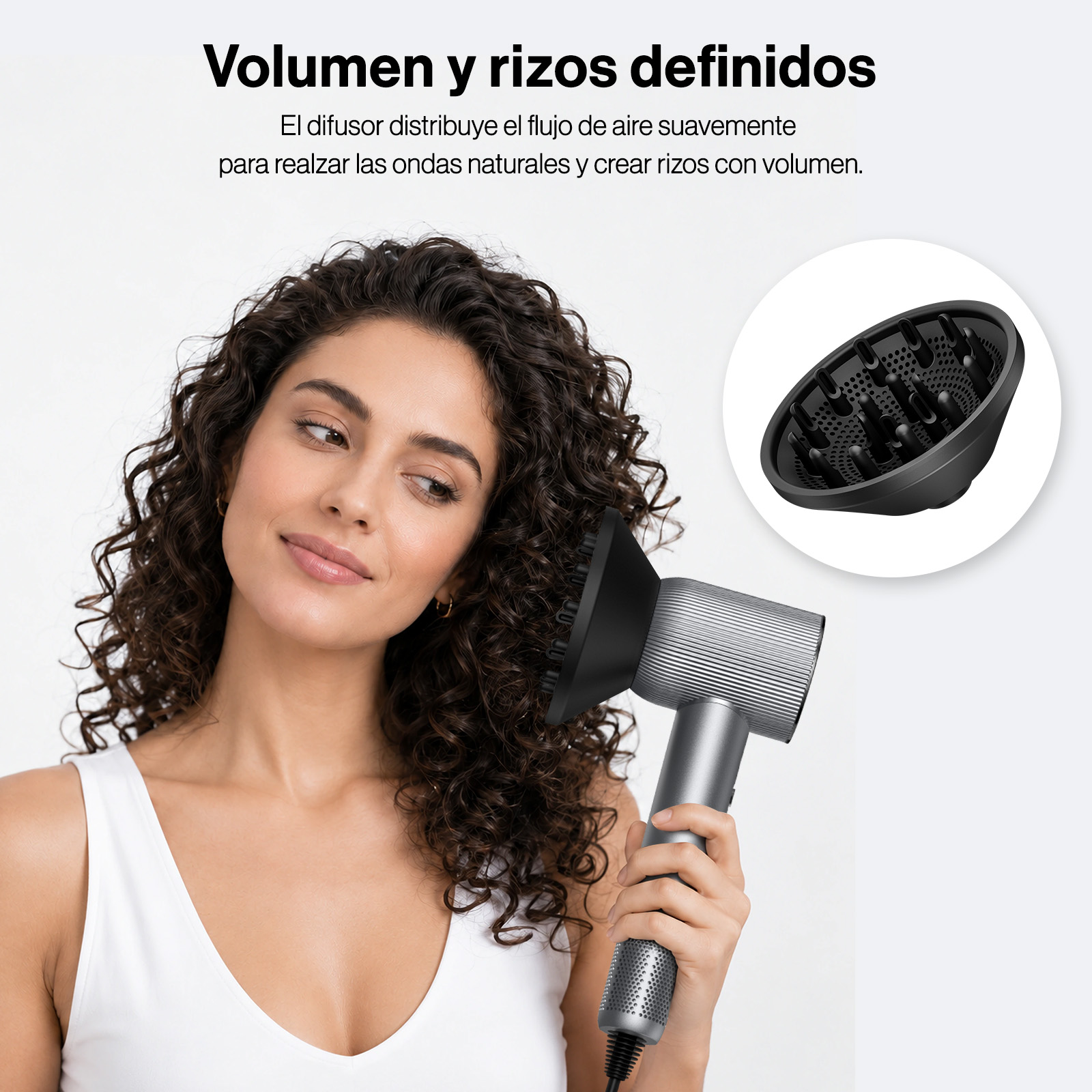 Una mujer con cabello rizado usa un secador plateado con un difusor negro.