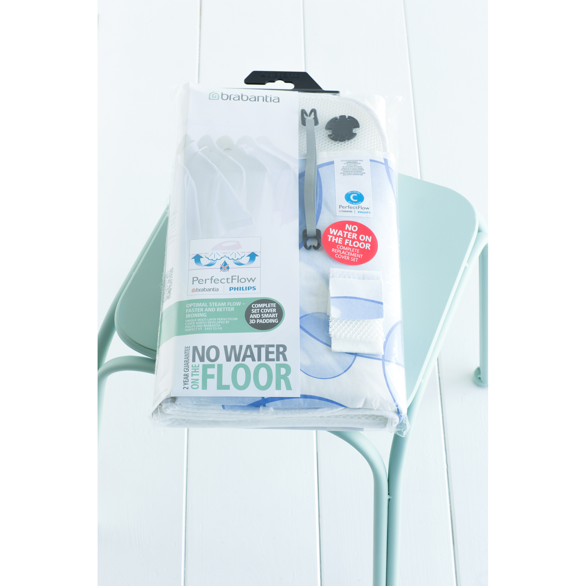Eingepackter Brabantia Bügelbrettbezug auf einem mintgrünen Stuhl auf weißem Holzboden.