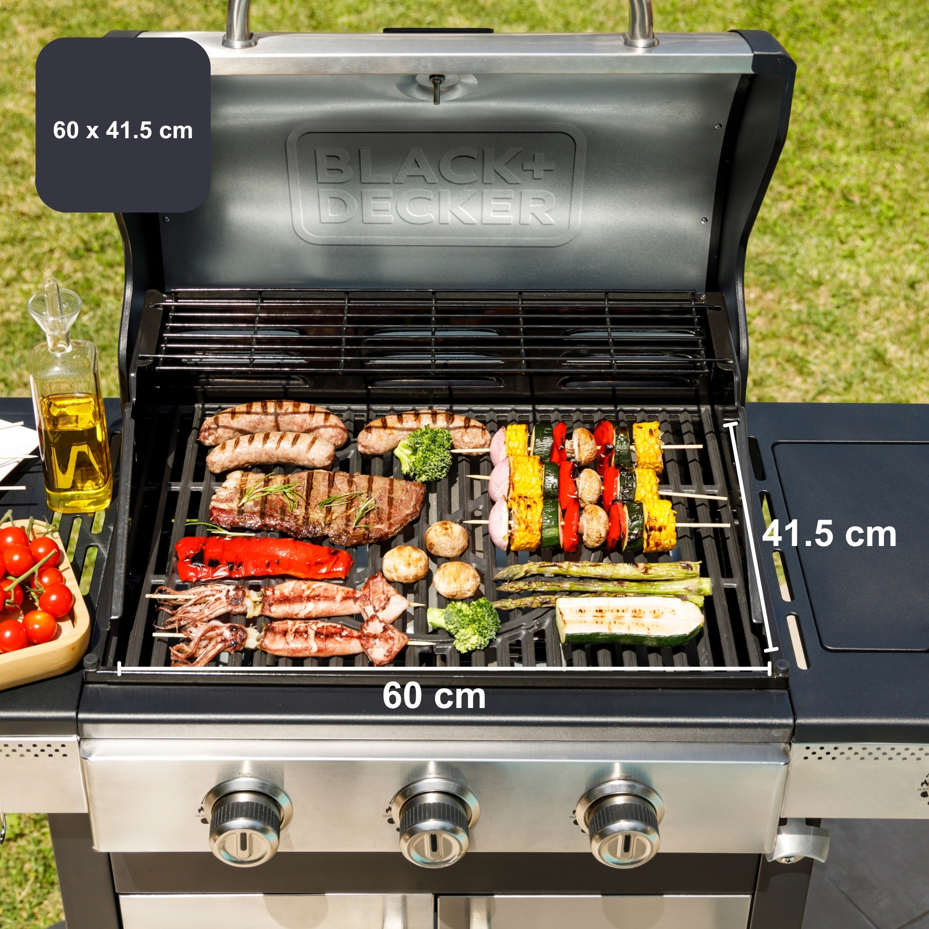 Grill Black+Decker z kielbasami, stekiem, szaszlykami, warzywami i olejem, wymiary 60x41,5 cm.