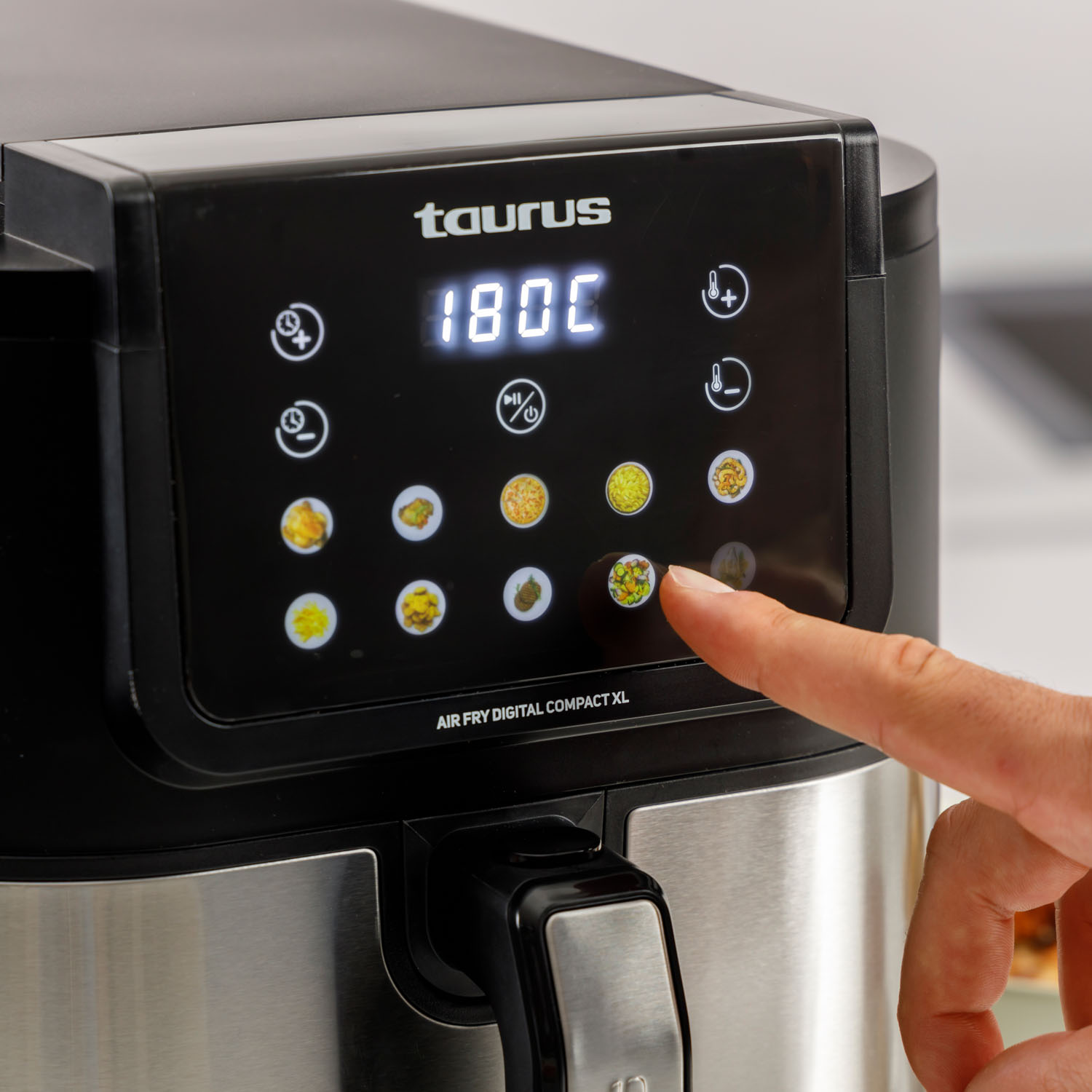 Ręka dotyka cyfrowego ekranu dotykowego frytkownicy beztłuszczowej Taurus Air Fry Digital Compact XL.