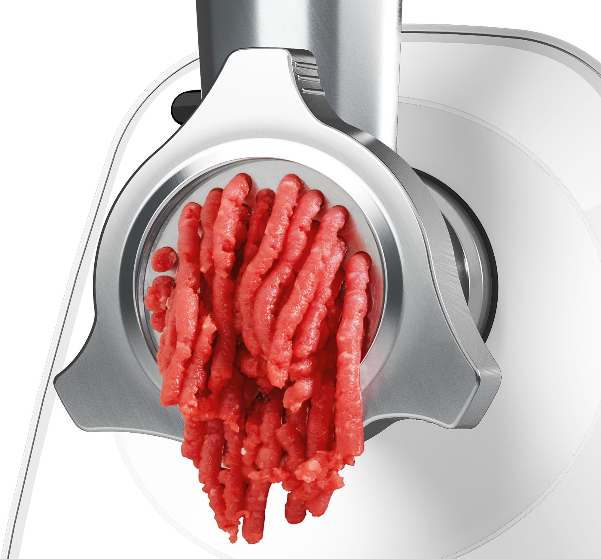 Carne picada roja fresca sale del disco moledor de una picadora.