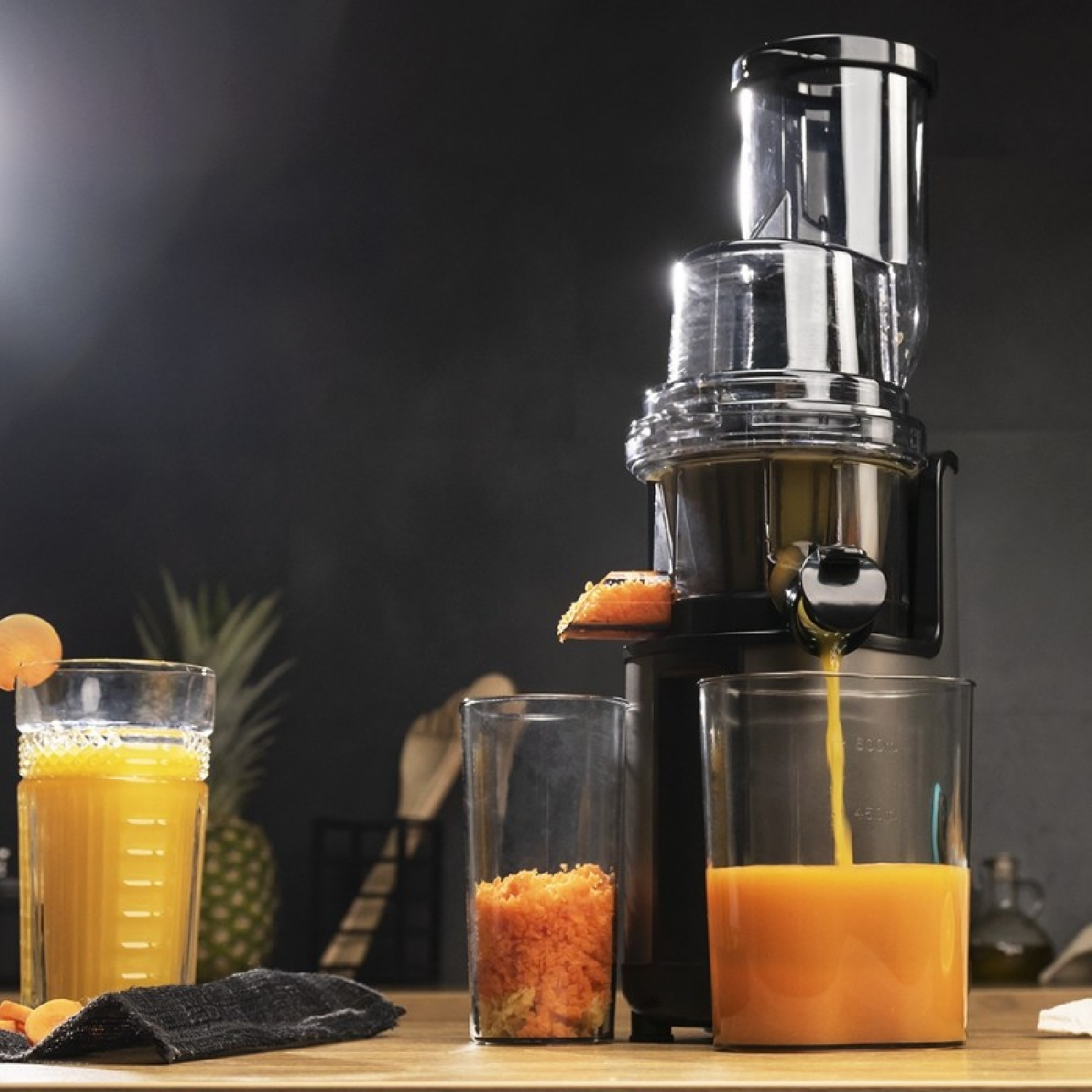 Un estrattore versa il succo in un bicchiere, accanto a succo e polpa.