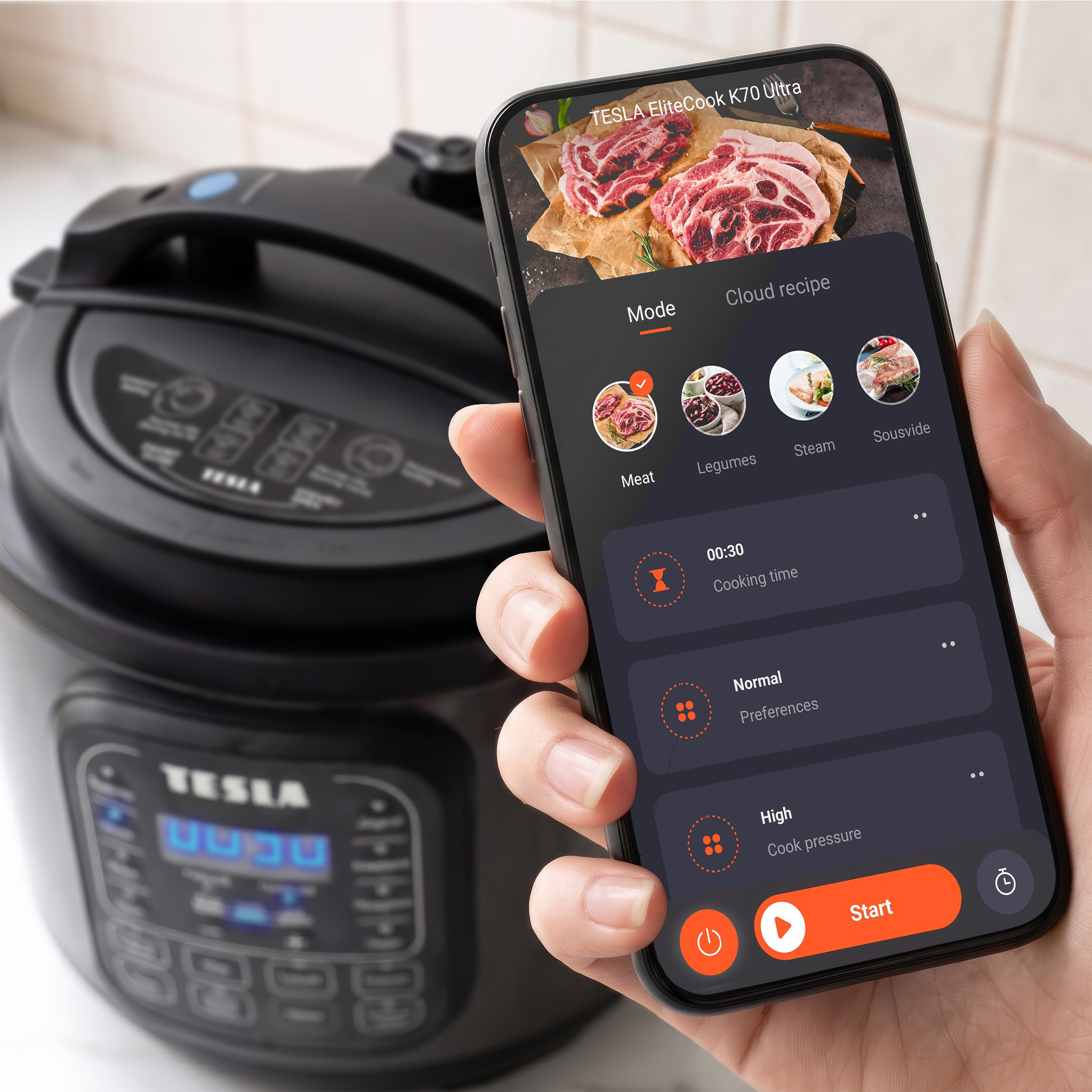 Una mano regge uno smartphone con un'app di cucina, con una pentola a pressione elettrica nera sullo sfondo.