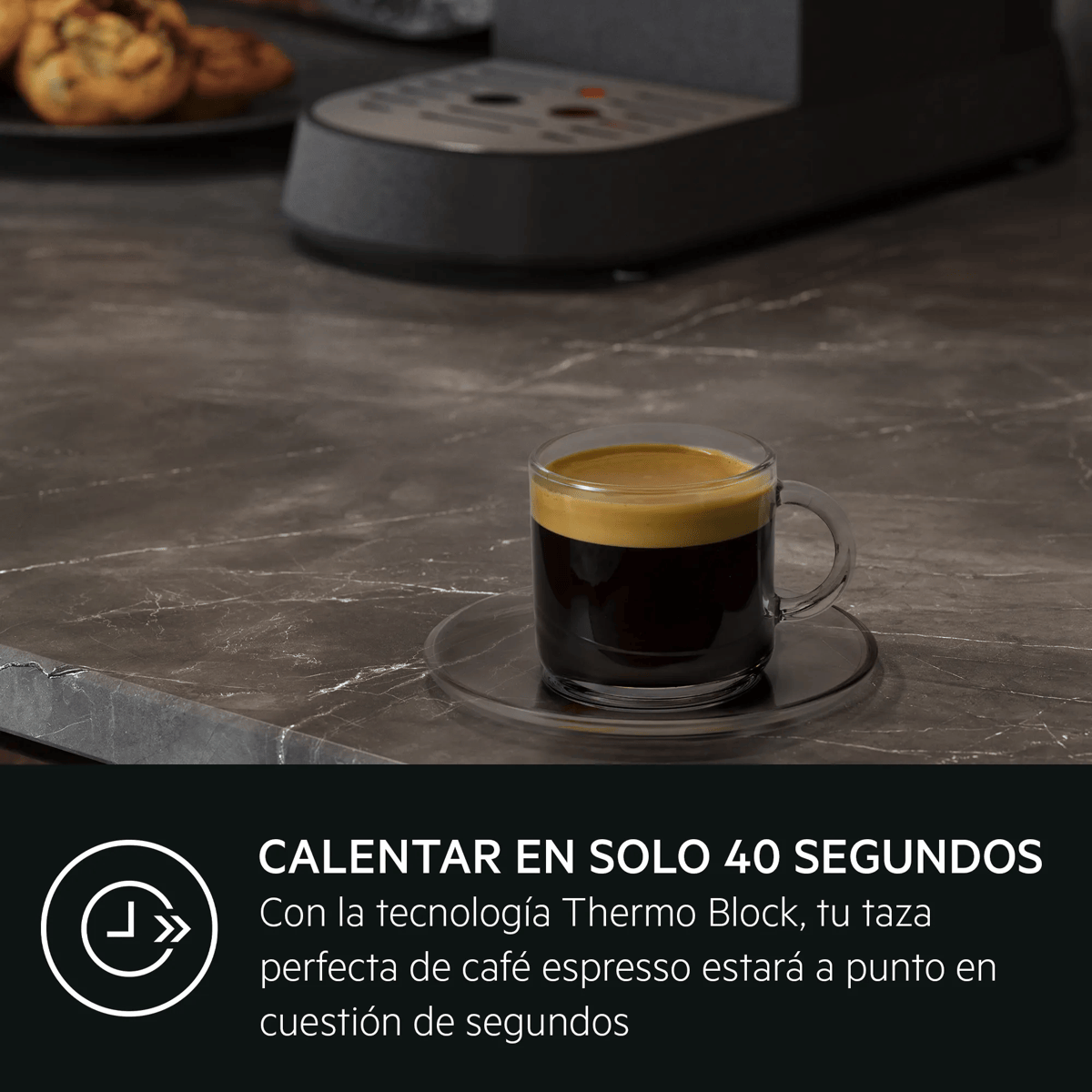 Eine Glastasse mit schwarzem Espresso und Crema steht auf einer Marmorarbeitsplatte neben einer Kaffeemaschine.