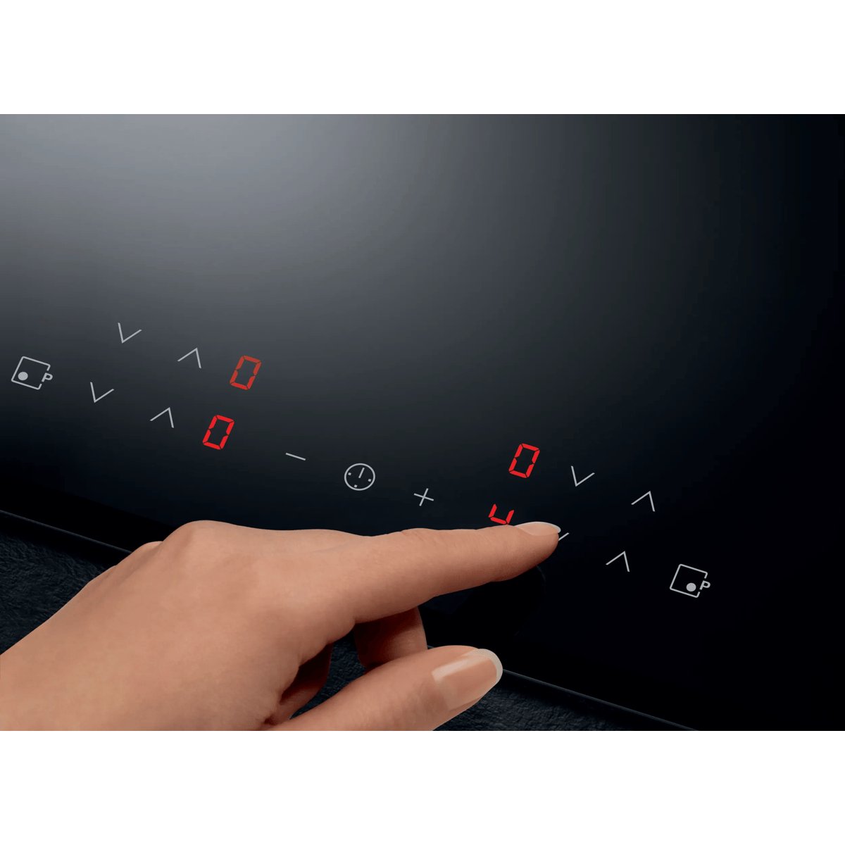 Una mano toca el panel de control táctil de una placa de inducción negra con números LED rojos.