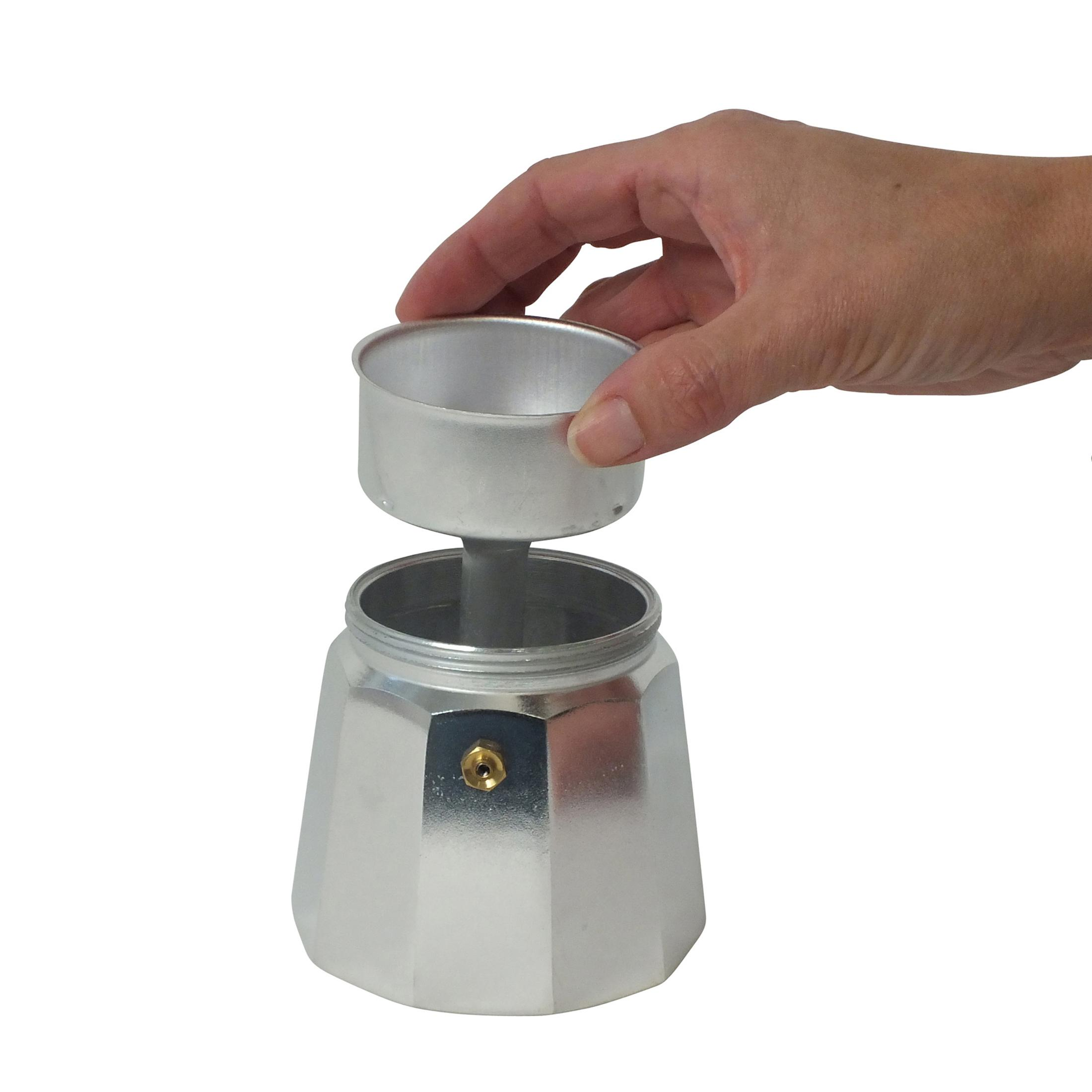 Une main insère l'entonnoir en métal dans la chambre inférieure d'une cafetière.