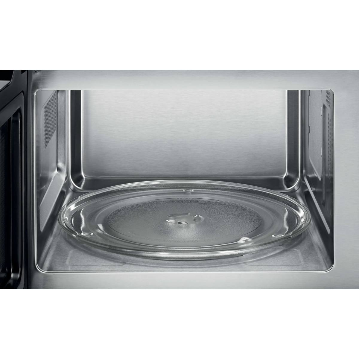 El interior de un microondas limpio con paredes de acero inoxidable y un plato giratorio de vidrio.