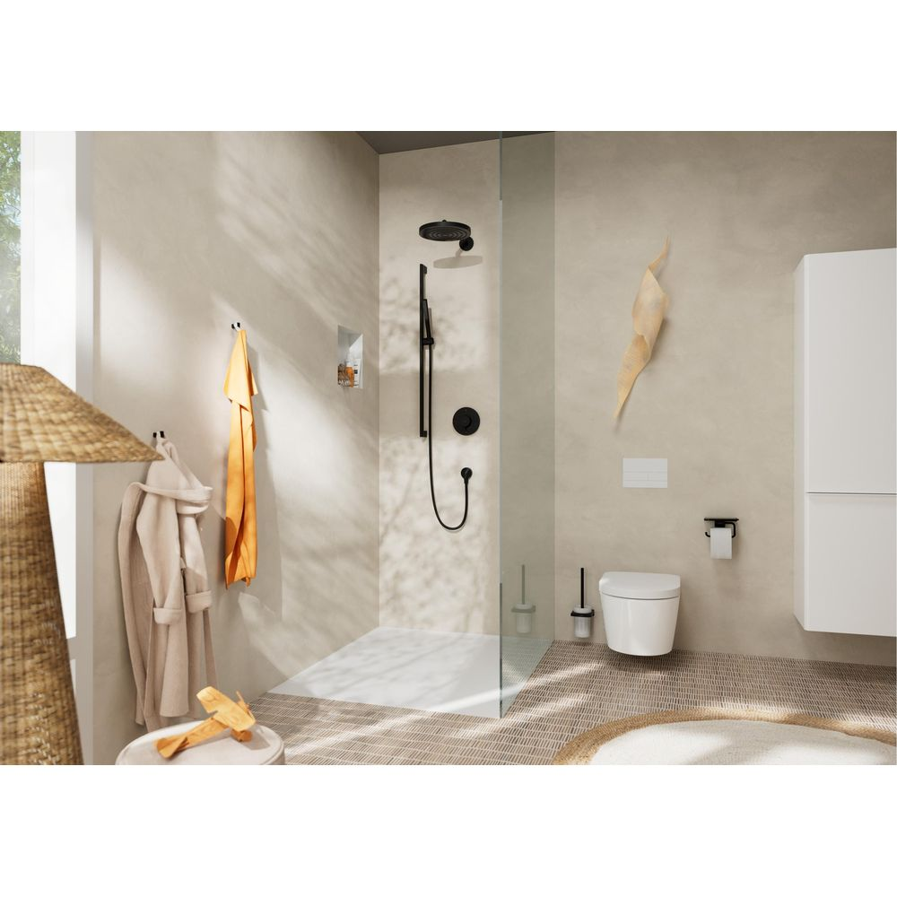 Modernes, beiges Badezimmer mit Glasdusche, weißer Toilette, gefliestem Boden und hängenden Bademänteln.