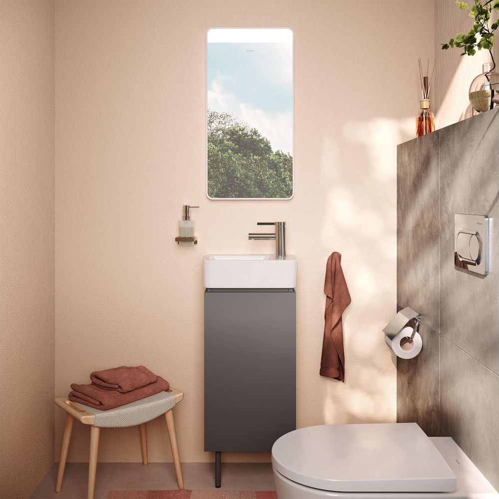 Ein modernes Bad mit dunklem Waschtisch, weißem Waschbecken, Spiegel, Toilette und Handtüchern auf einer Bank.