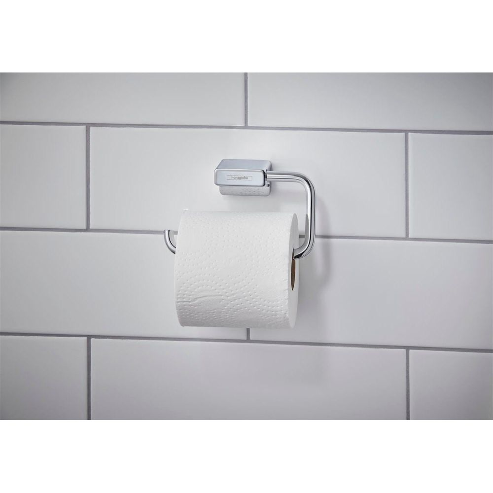 Ein glänzender Toilettenpapierhalter aus Chrom mit weißem Toilettenpapier an einer hellen Kachelwand.
