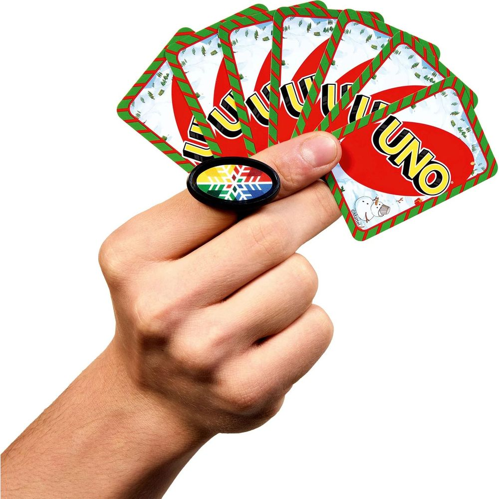 Una mano tiene un mazzo di carte Uno natalizie e indossa un anello a fiocco di neve.