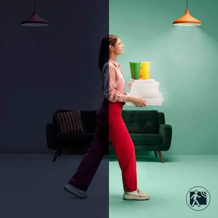 Una mujer camina de una habitación oscura a una luminosa de color verde menta, cargando cajas y tazas.