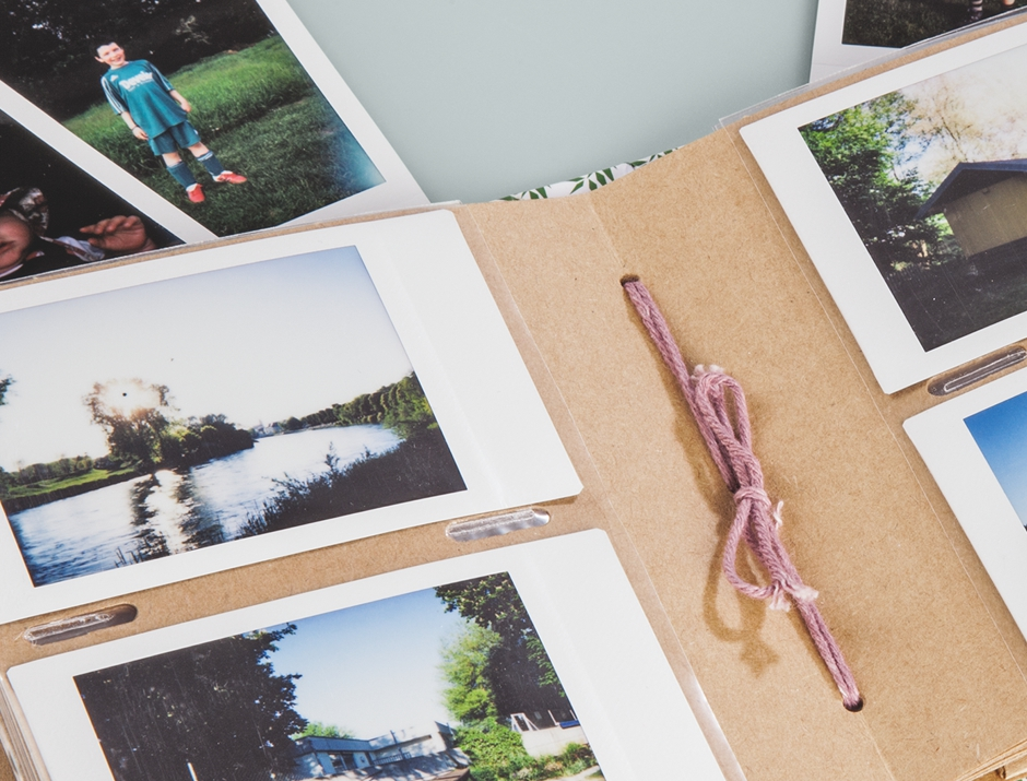 Un album fotografico aperto in carta marrone mostra varie foto polaroid, inclusi paesaggi e persone.