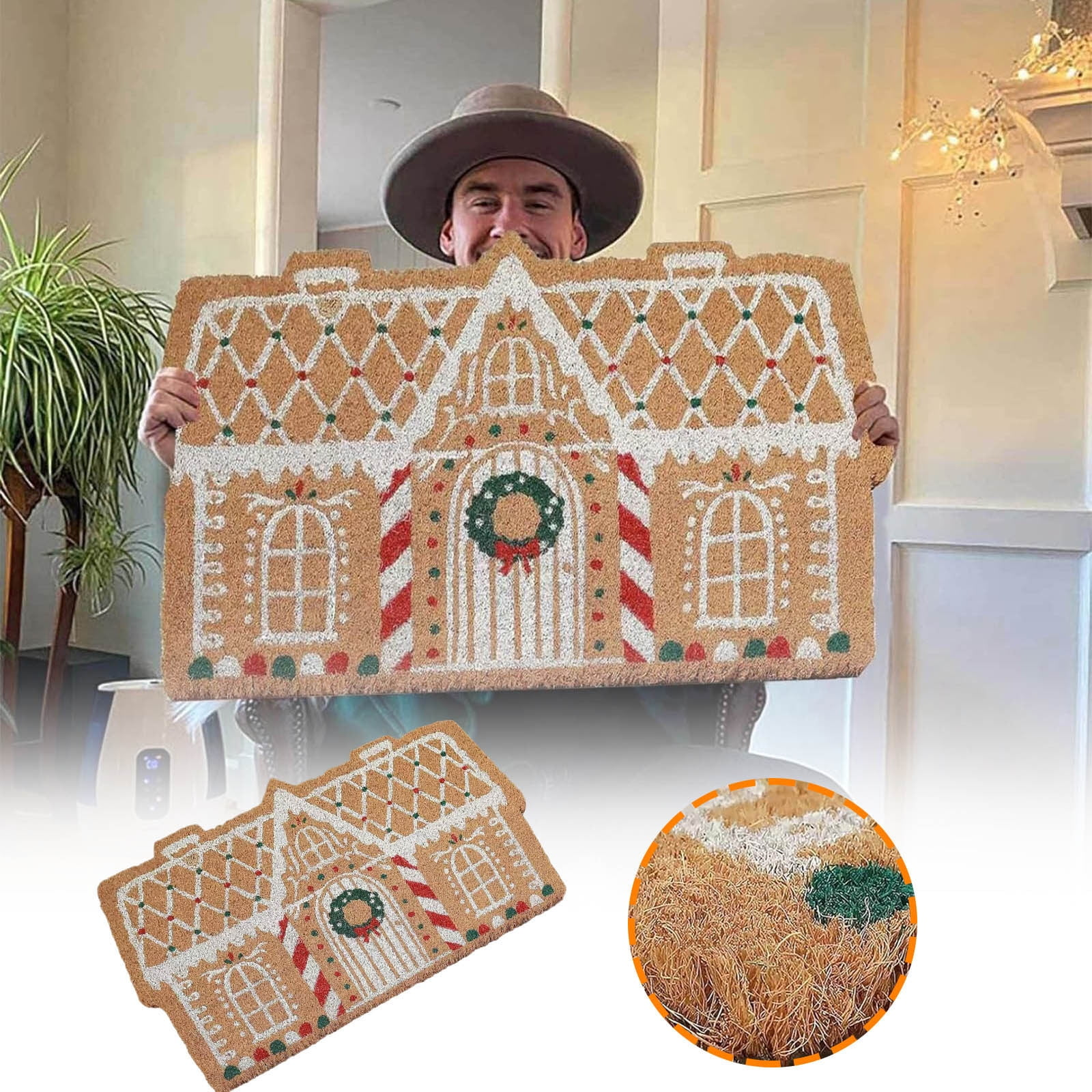 Ein Mann mit Hut hält eine große, als Lebkuchenhaus gestaltete Fußmatte in die Höhe.