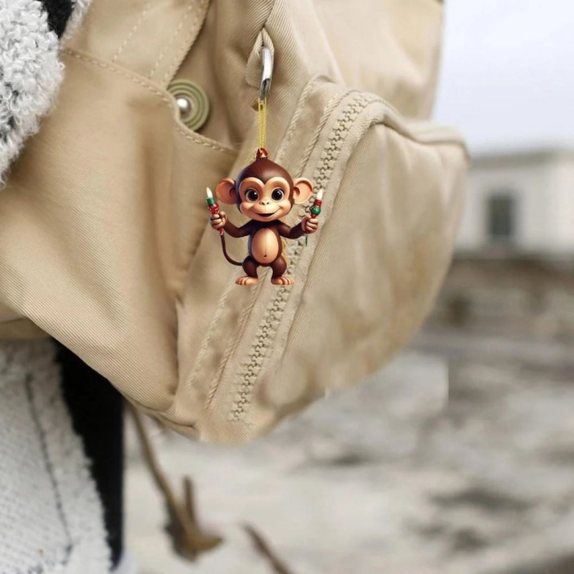 Ein kleiner Affe als Anhänger am Reißverschluss eines beigen Rucksacks.