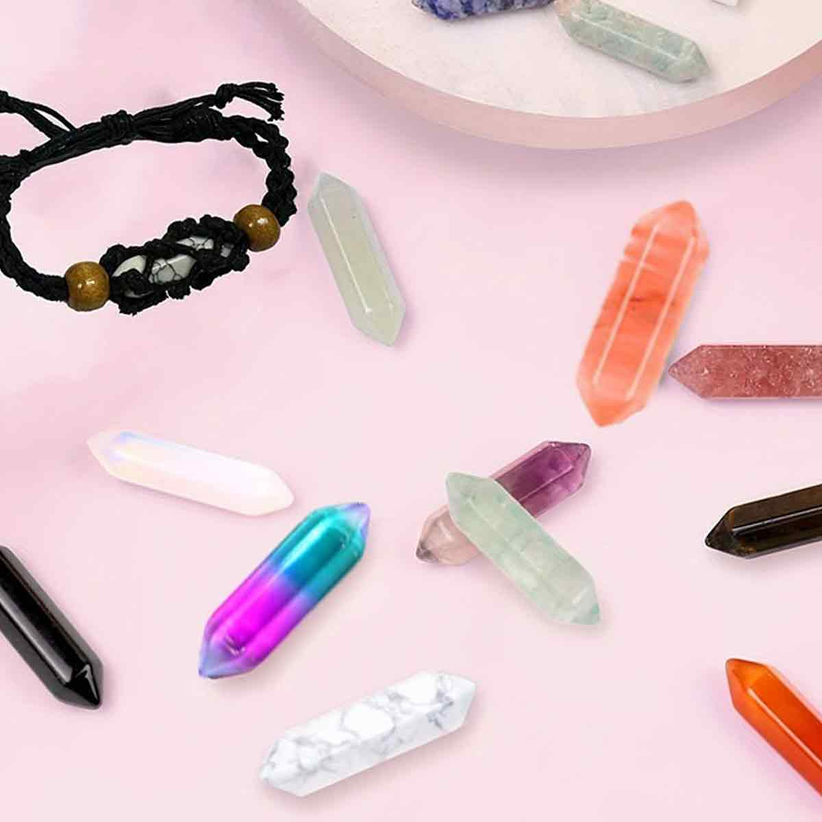 Ein schwarzes Armband und mehrere bunte, polierte Kristallspitzen auf rosa Hintergrund.