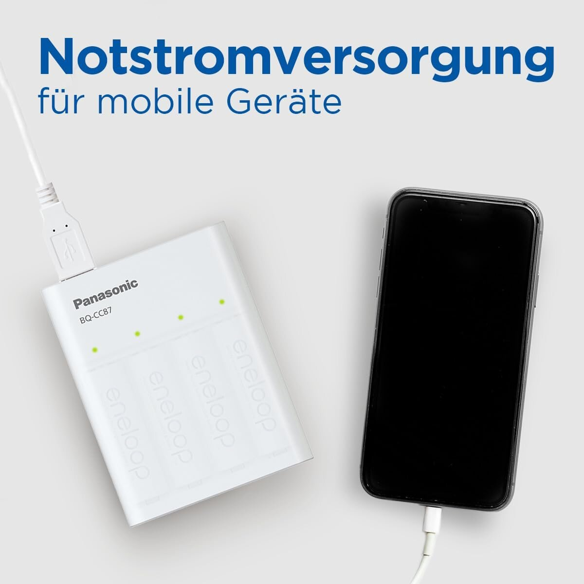 Ładowarka Panasonic zasila smartfon, z niemieckim tekstem o zasilaniu awaryjnym.