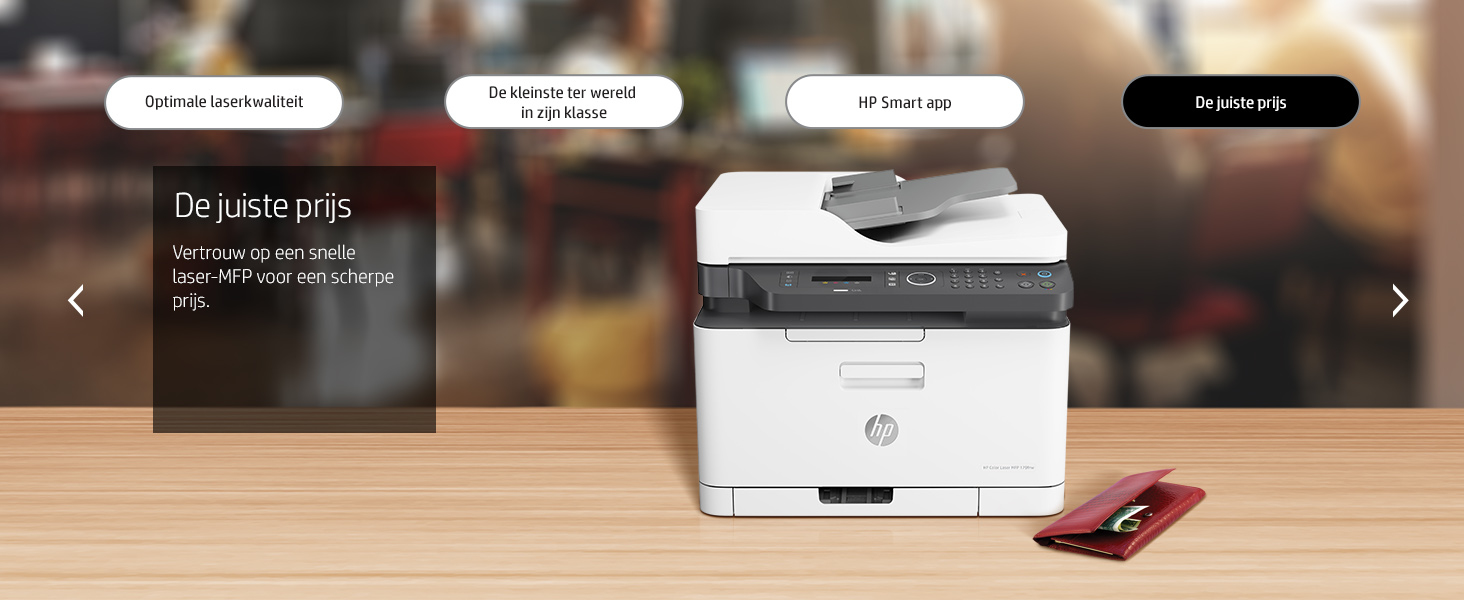 Ein weißer HP-Laserdrucker steht auf einem Holztisch neben einer roten Brieftasche vor einer verschwommenen Kulisse.