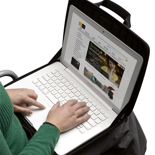 Person tippt auf einem weißen Laptop in einer schwarzen Tasche.