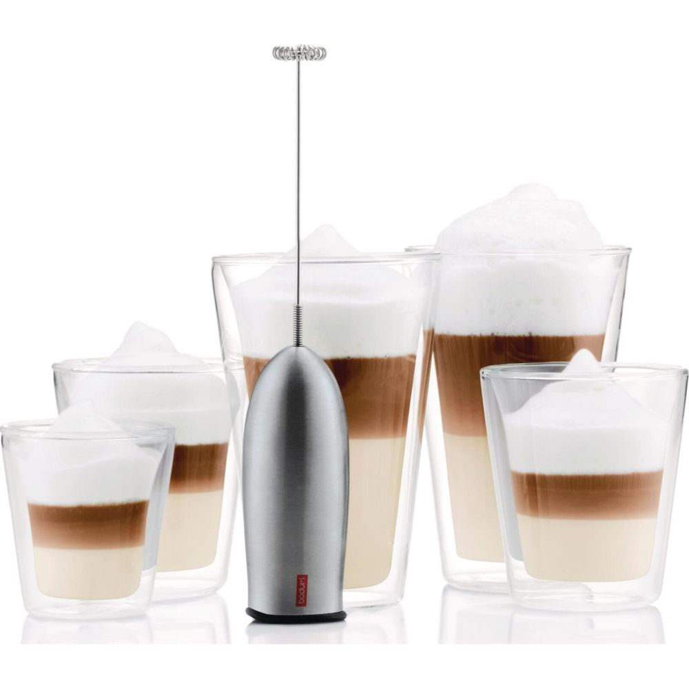 Un mousseur à lait se dresse devant cinq verres différents de café en couches.