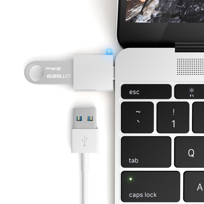 Un concentrador USB blanco y un cable USB están conectados a una computadora portátil.