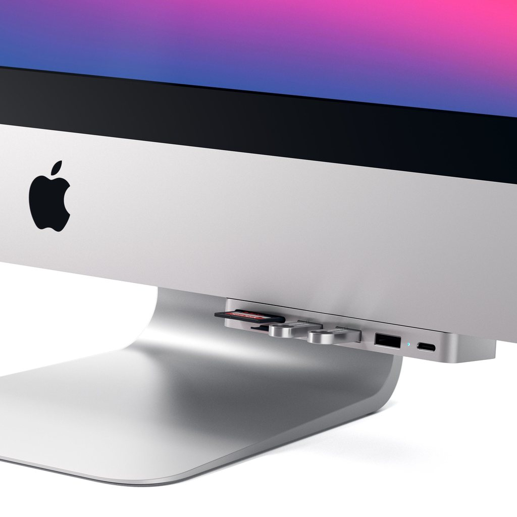 Un concentrador USB plateado está conectado a la parte inferior de una computadora iMac con tarjetas y puertos.