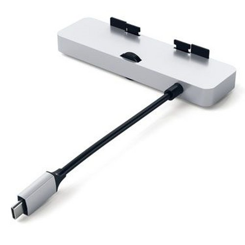 Un concentrador USB-C plateado con un cable adjunto reposa sobre una superficie blanca.