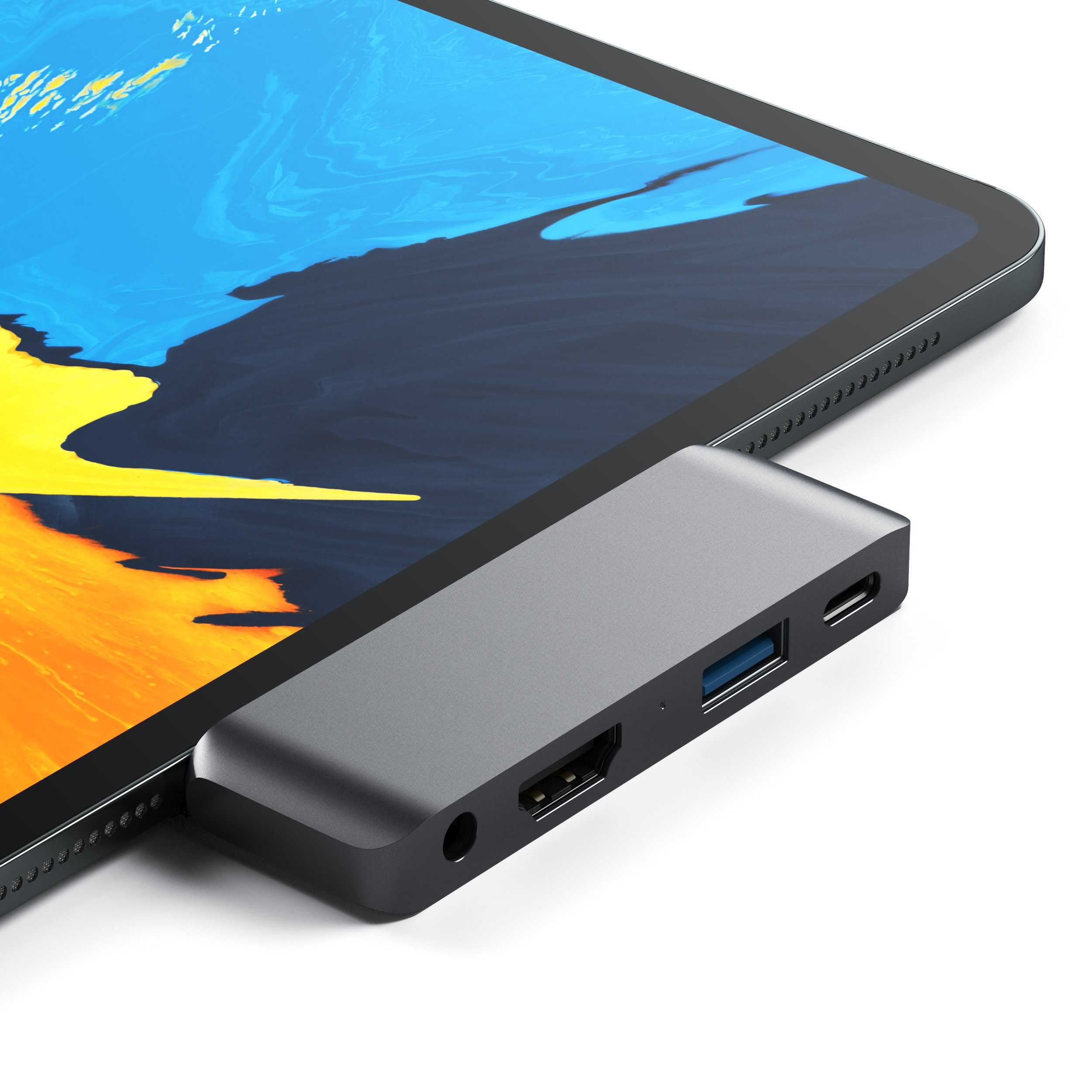 Un hub USB-C grigio è collegato al lato di un tablet, dotato di porte HDMI, USB e audio.