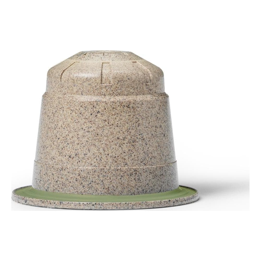 Una capsula di caffè beige screziata con un bordo verde su sfondo bianco.