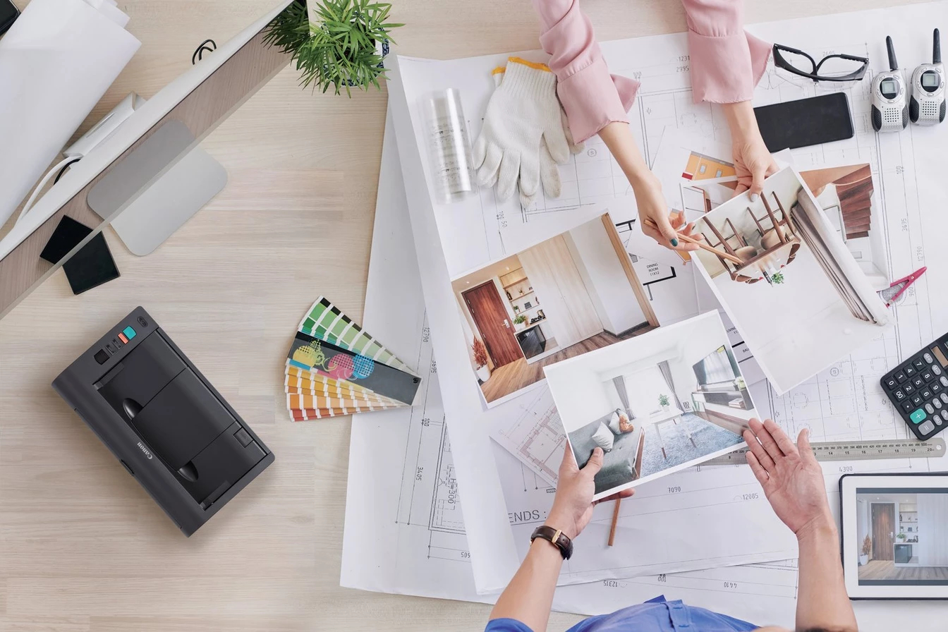 I designer esaminano progetti architettonici, campioni e foto d'interni su una scrivania.
