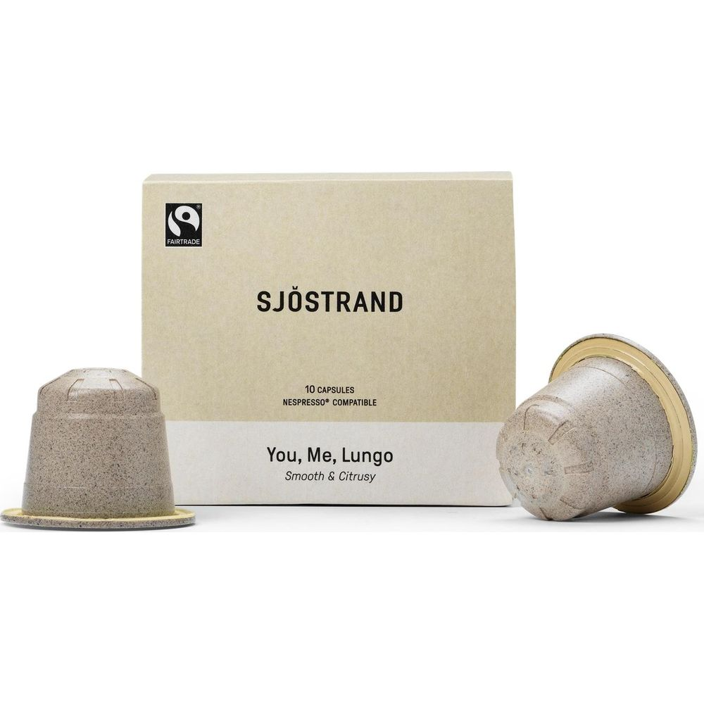 Scatola di capsule di caffè Sjöstrand con due capsule beige su superficie bianca.