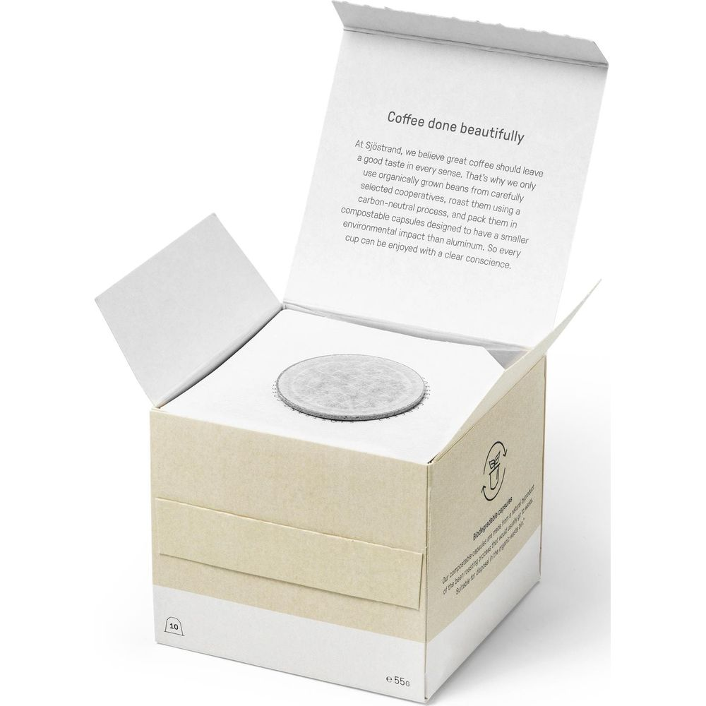 Scatola di cartone aperta con capsule di caffè compostabili e testo esplicativo.