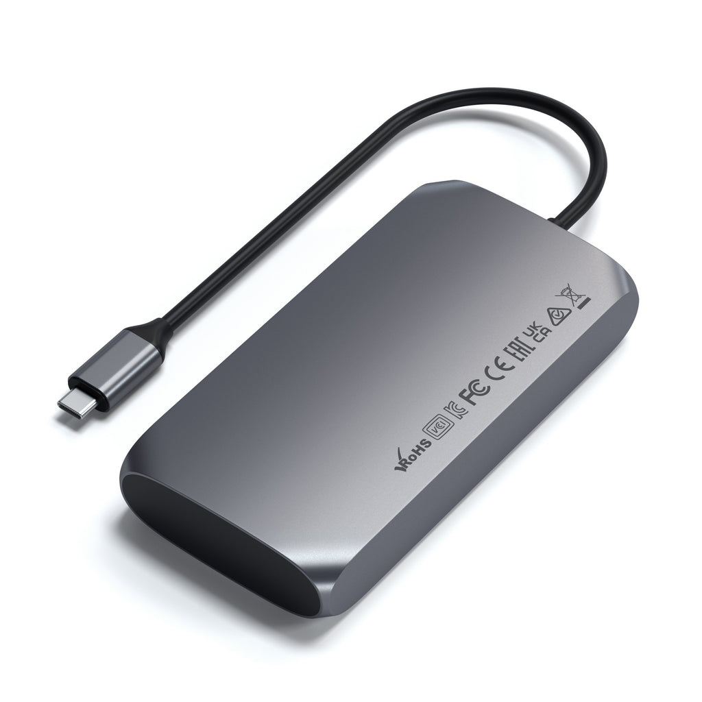Concentrador USB-C gris con un cable negro y conector sobre fondo blanco.