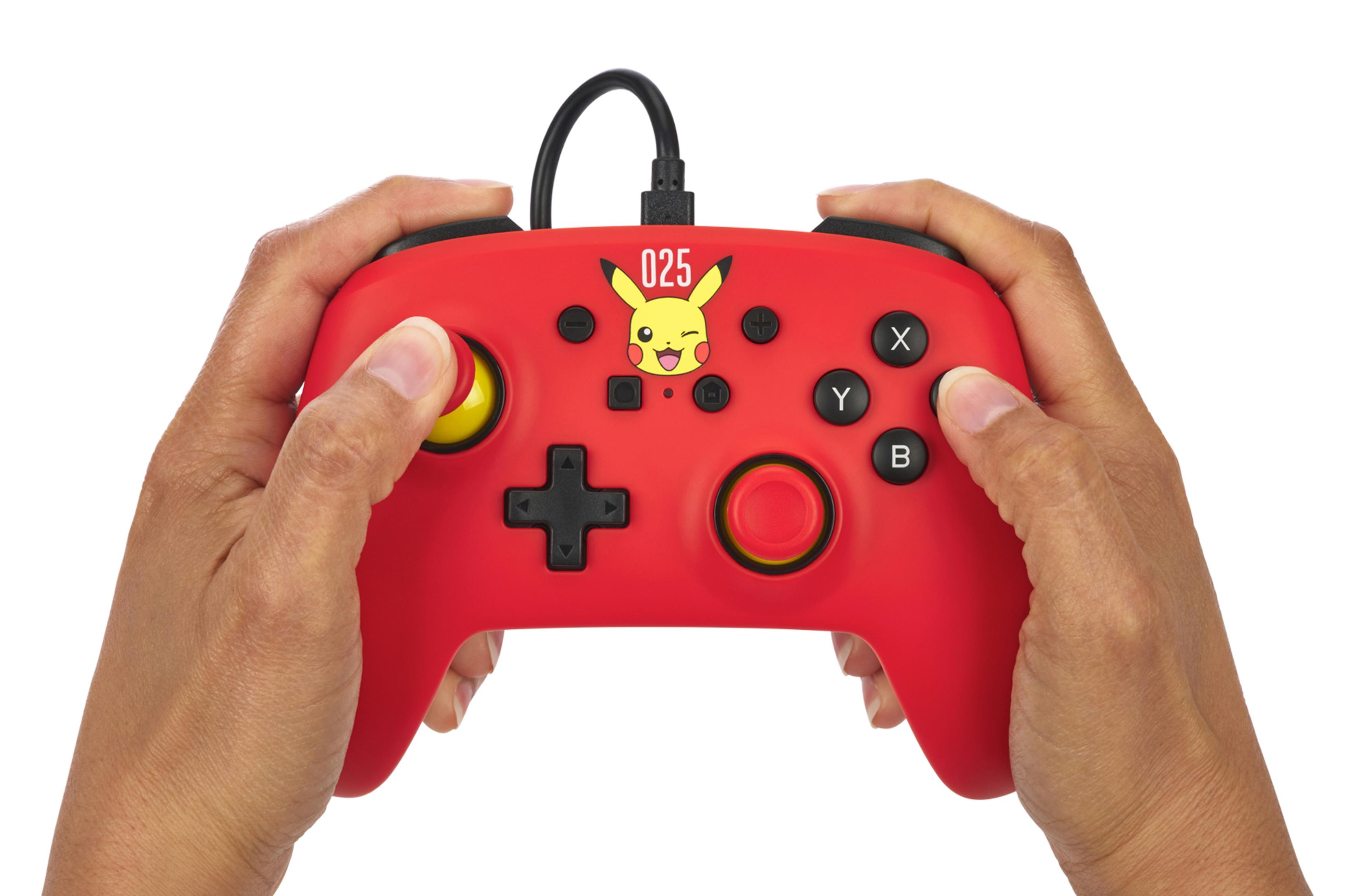 Due mani tengono un controller di gioco rosso a tema Pikachu su sfondo bianco.