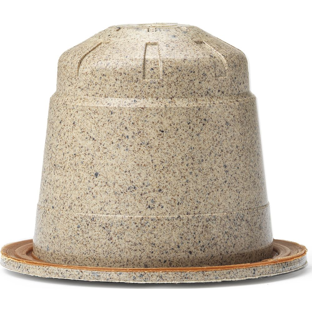 Una capsula di caffè beige maculata con bordo scanalato su sfondo bianco.