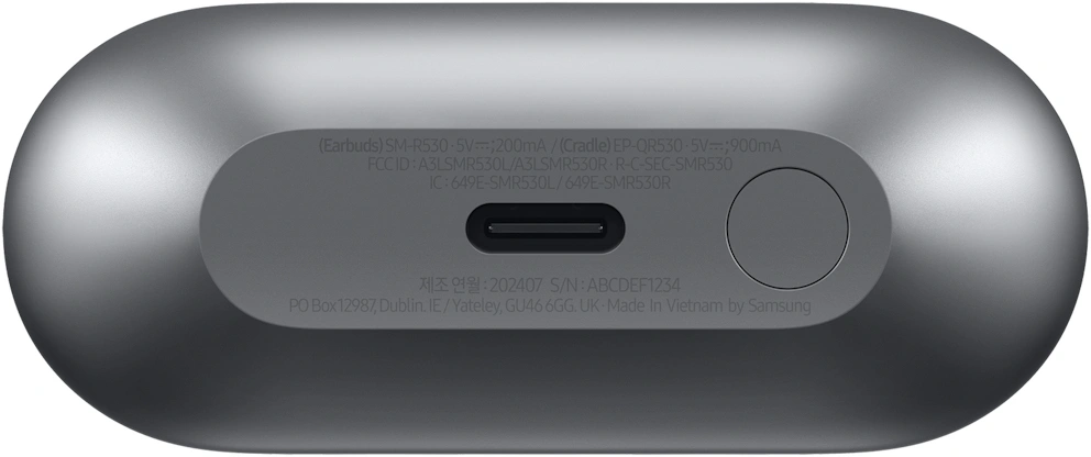 Parte inferior de un estuche de carga gris con puerto USB-C, botón y texto regulatorio.