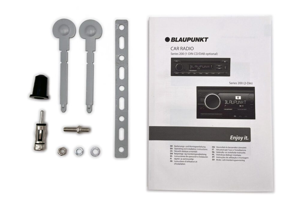 Un manuale autoradio Blaupunkt si trova accanto ad accessori e strumenti.