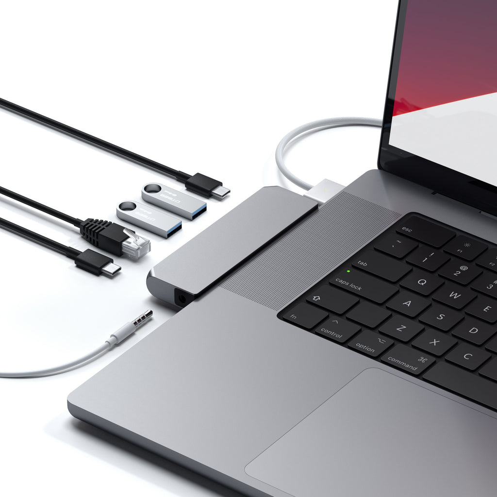 Una laptop con un concentrador USB-C gris conectado al lateral, rodeado de cables y unidades USB.
