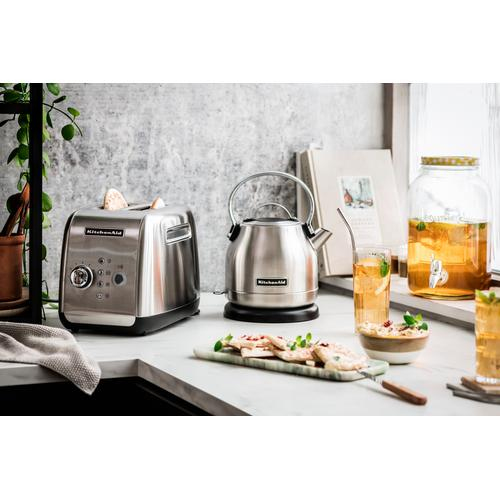 Eine Küchenarbeitsplatte mit silbernem Toaster, Wasserkocher, Essen, Getränken und einem großen Glas.