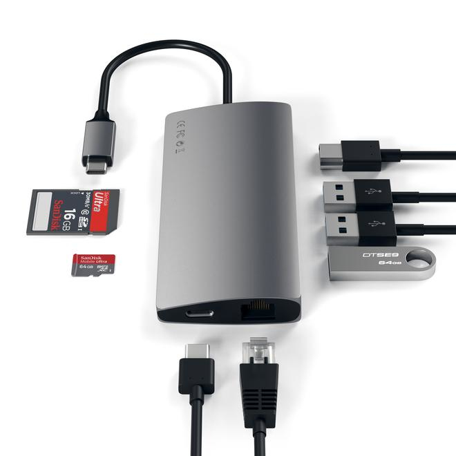 Ein silberner USB-C-Hub mit angeschlossenen Kabeln, SD-Karten und einem USB-Stick vor weißem Hintergrund.