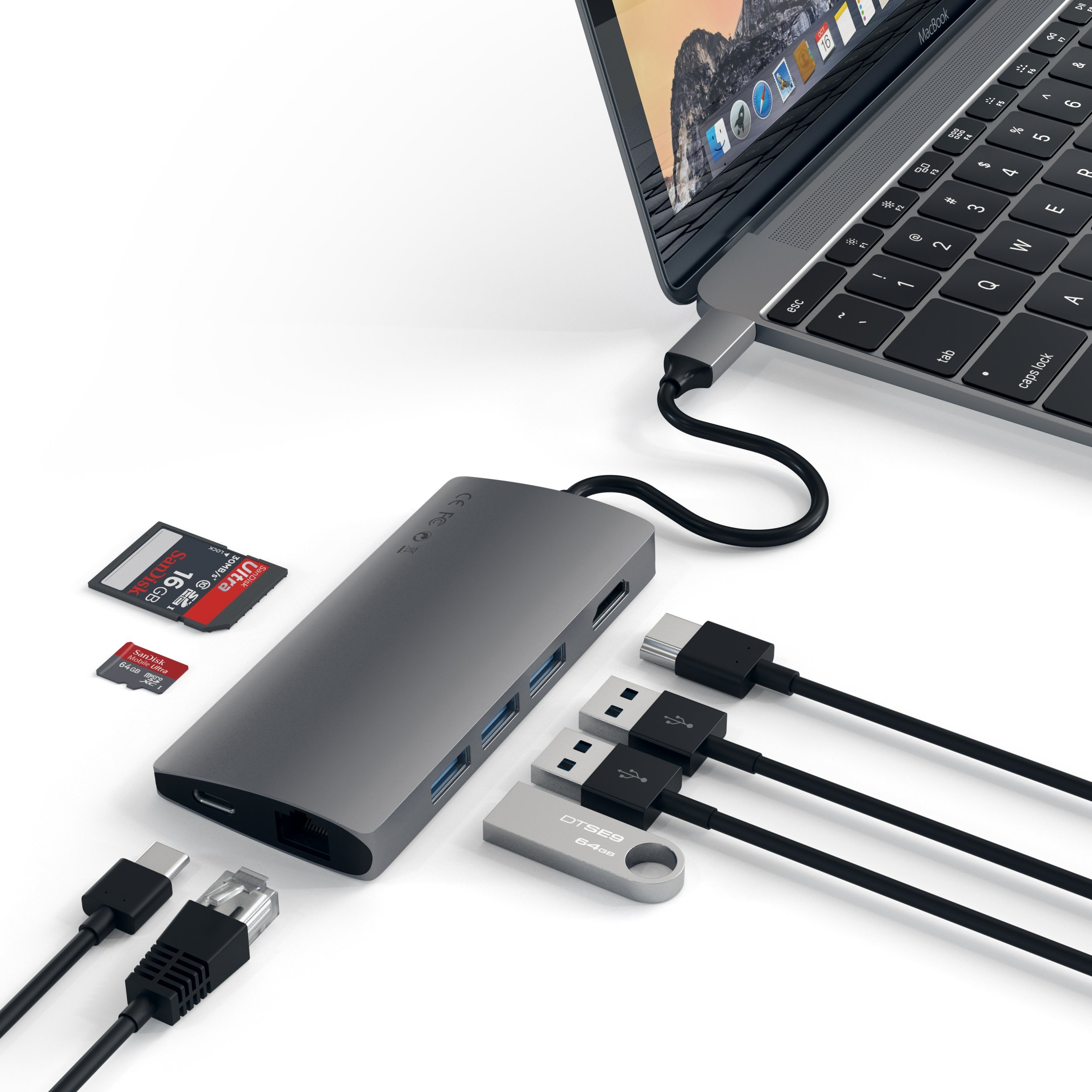 Ein grauer USB-C-Hub ist an ein MacBook angeschlossen und mit verschiedenen Kabeln und Speicherkarten verbunden.