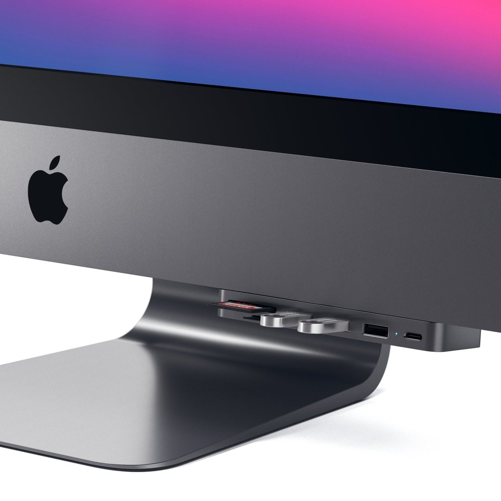 Un monitor de computadora gris con un concentrador conectado debajo, mostrando puertos USB y SD.