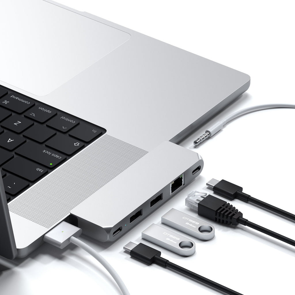 Concentrador USB-C plateado conectado a un portátil, con varios cables y unidades USB sobre fondo blanco.